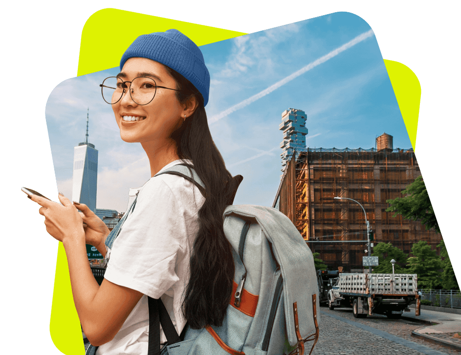 A smiling young woman looks away while holding her phone in front of a landmark. She carries a backpack which will be kept safe at a Bounce location while she explores.